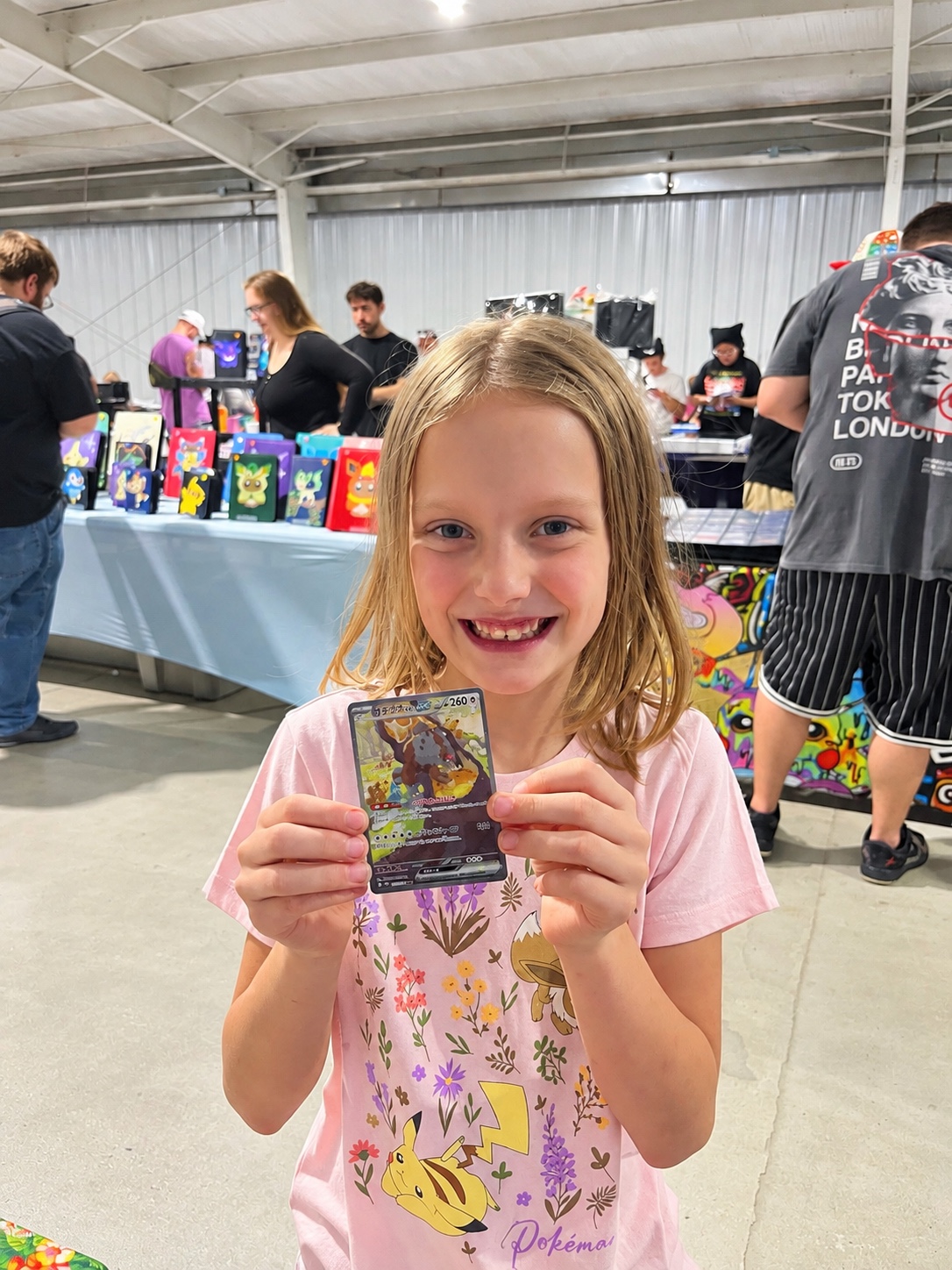 Young collector smiling and holding a trading card at a card show