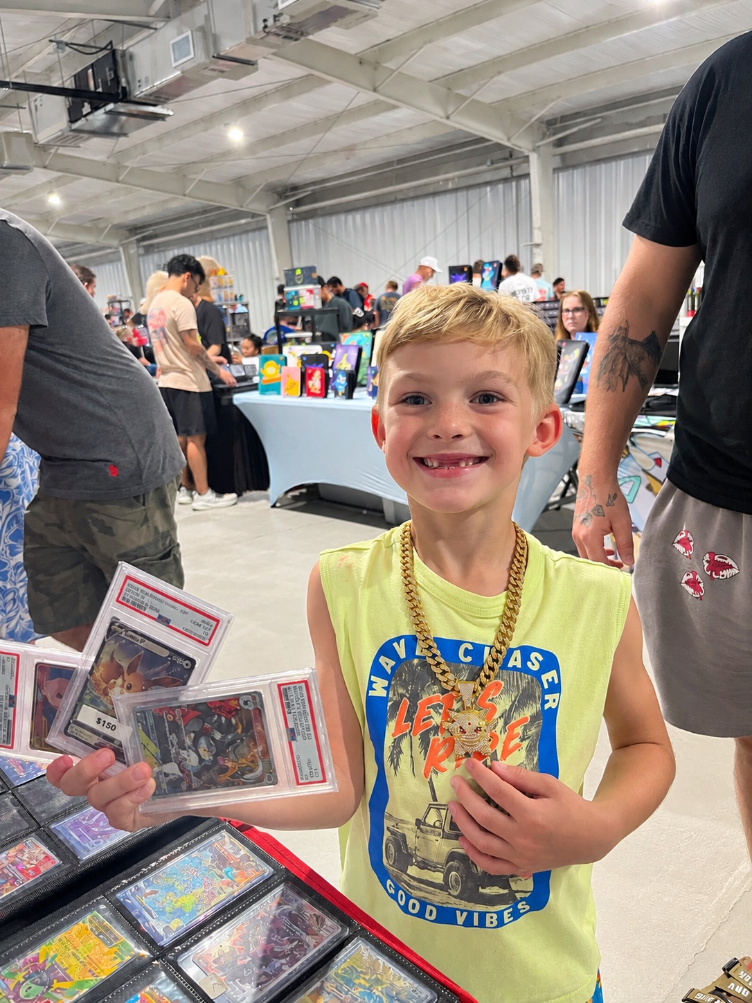 Young collector smiling while holding graded cards at a card show