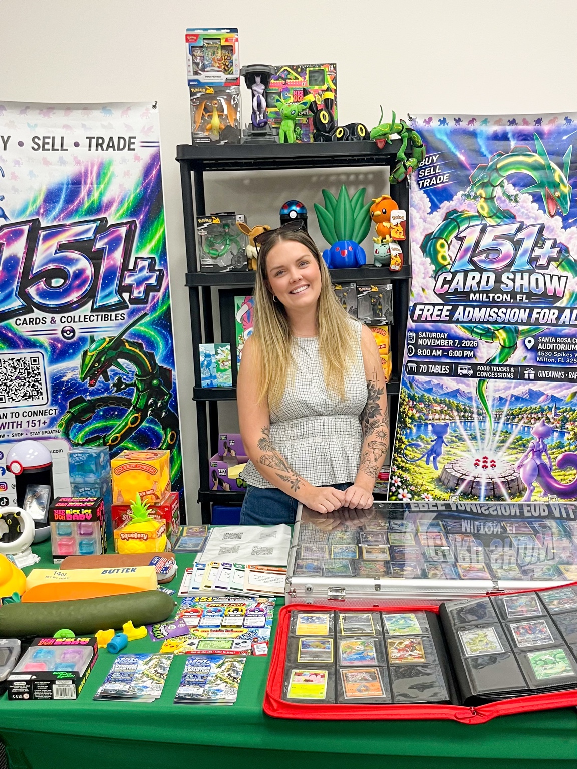 Collector smiling behind a table of trading cards and 151 Plus banners