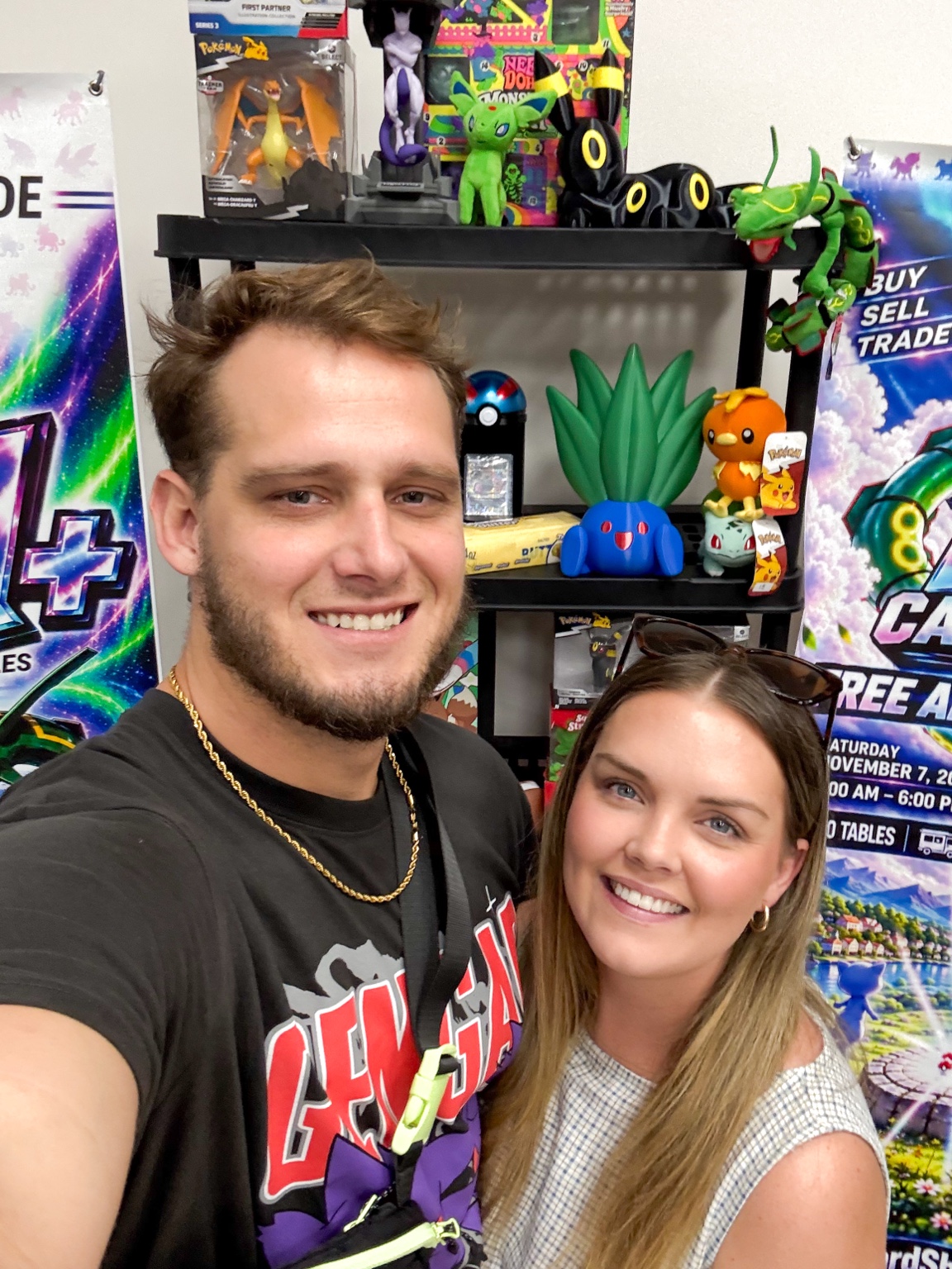 Two collectors smiling for a photo in front of a trading card display